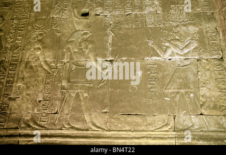 Hieroglyphen und Bas Reliefschnitzen des Pharao auf der rechten Seite, und die Götter Ra und Horus auf der linken, Edfu Tempel, Ägypten Stockfoto