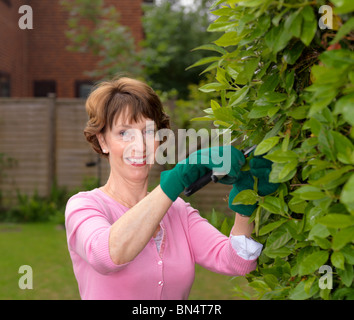 Glücklich senior Frau in rosa Top, Gartenarbeit. Stockfoto