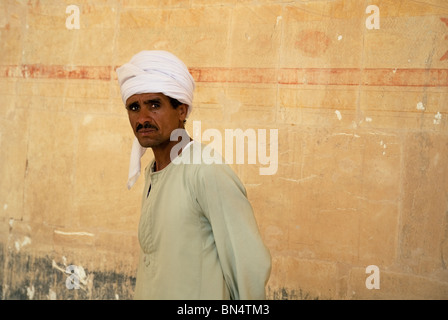 Ein ägyptischer Mann trägt einen traditionellen Galabia Stand in der Nähe einer Wand, die Leichenhalle Tempel der Hatschepsut, Luxor, Oberägypten Stockfoto