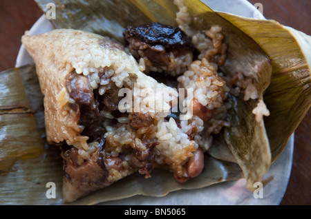 Chinesische Reis Knödel Zong Zi / Ba Zhang - Reis, Schweinefleisch, Pilzen und Erdnüssen in Blätter eingewickelt Stockfoto
