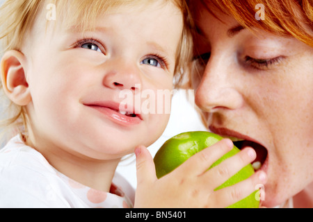 Porträt der Frau bereit, Reifen Apfel in die Hände ihres Kindes zu beißen Stockfoto