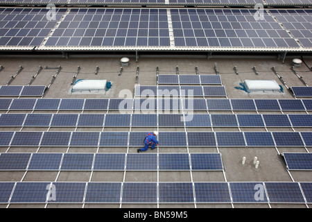 Bau einer großen Solaranlage auf einem riesigen Flachdach einer Lagerhalle. Stockfoto