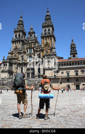 Zwei Pilger mit Rucksäcken und Mitarbeiter stehen vor der Kathedrale, Santiago de Compostela, Galicien, Nordspanien. Stockfoto