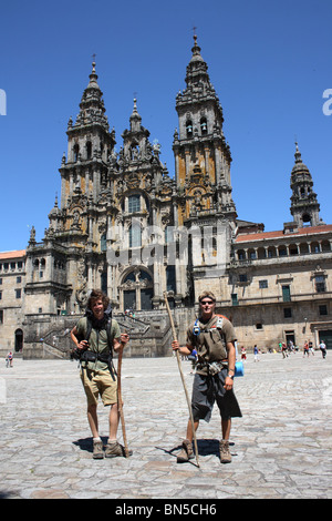 Zwei Pilger mit Rucksäcken und Mitarbeiter stehen vor der Kathedrale, Santiago de Compostela, Galicien, Nordspanien. Stockfoto