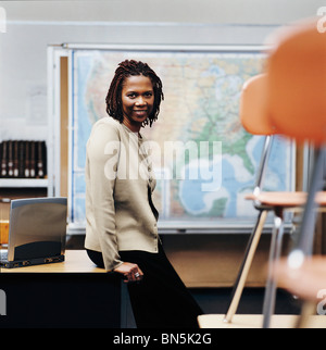 Afrikanische amerikanische Lehrer sitzen am Schreibtisch im Klassenzimmer Stockfoto