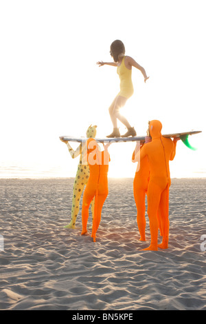 Leute, gekleidet in seltsamen Kostümen mit Surfbrett Stockfoto