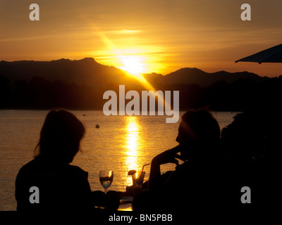 Ein paar beobachten den Sonnenuntergang über dem Meer im mallorquinischen Ferienort Alcudia. Stockfoto