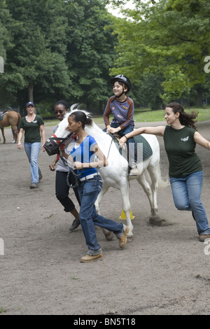 Behinderte Kinder erhalten eine Entwicklungstherapie, die das Reiten von Pferden erlernt, bekannt als Hippotherapie. Die Hippotherapie ist eine körperliche, berufliche und sprachliche Tätigkeit Stockfoto