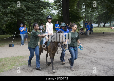 Behinderte Kinder erhalten eine Entwicklungstherapie und lernen, Pferde zu reiten, bekannt als Hippotherapie i9n Prospect Park, Brooklyn, NY. Stockfoto