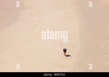 Ein Mann Mäander und hinterlassen Spuren auf Porthcurno Strand, Cornwall, UK. Stockfoto