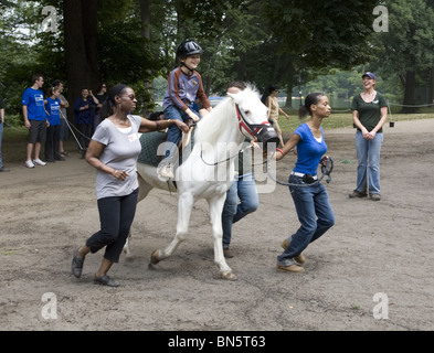 Behinderte Kinder erhalten Entwicklungs-Therapie, bekannt als Hippotherapie Reiten lernen. Prospect Park in Brooklyn, NY Stockfoto