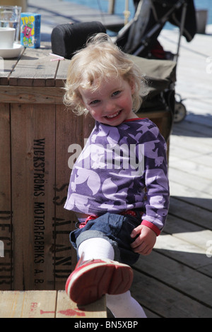 Niedlichen Kleinkind Mädchen Baby in kurzen Hosen mit roten Schuhen posiert mit Lächeln locken für Kamera Modell veröffentlicht Stockfoto