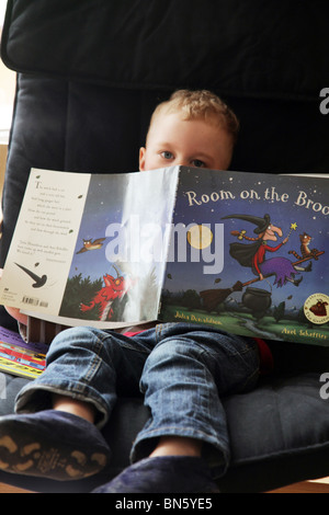 Junge Kleinkind beim Lesen des Buches Zimmer auf den Besen von Julia Donaldson-Axel Scheffler saß allein auf einem Stuhl Modell veröffentlicht Stockfoto