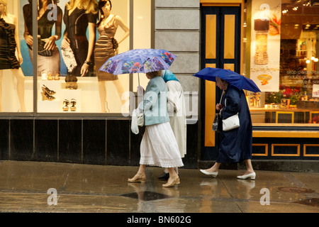 Drei Frauen mit Sonnenschirmen an einem regnerischen Tag. Rue Saint-Jean, Quebec, Kanada. Stockfoto
