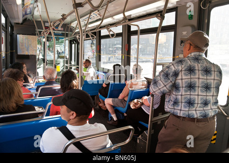 Innere des späten Modell New York Transit Authority New York City Bus mit sitzenden & stehende Passagiere Stockfoto