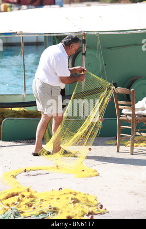 Ein Fischer flickt seine Netze auf dem Kai in Georgioupolis, Kreta, Griechenland. Stockfoto