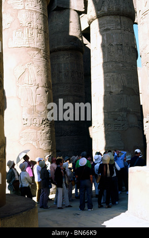 Gruppe von chinesischen Touristen zwischen den massiven Säulen der großen Säulenhalle am Karnak-Tempel in Luxor. Stockfoto