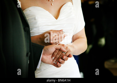 Braut hält Bräutigam Hochzeit Ring Band während der Austausch der Ringe Teil einer traditionellen Hochzeit Trauung UK Stockfoto