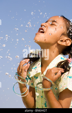 Indisches Mädchen Spritzwasser auf, sich gegen den blauen Himmel. Indien Stockfoto