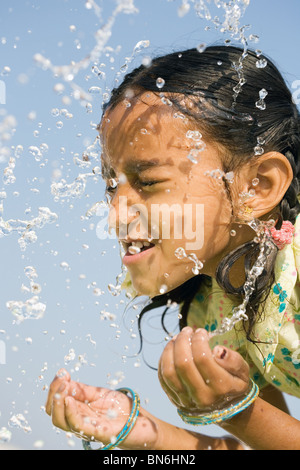 Indisches Mädchen Spritzwasser auf, sich gegen den blauen Himmel. Indien Stockfoto