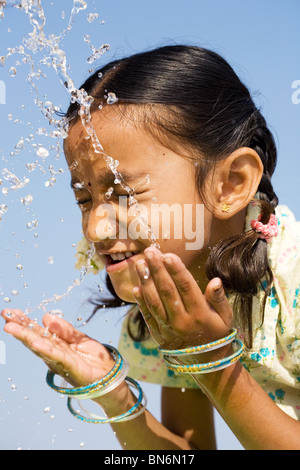 Indisches Mädchen Spritzwasser auf, sich gegen den blauen Himmel. Indien Stockfoto