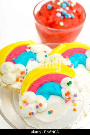 Bunt verziert Regenbogen Cookies auf einem Teller, begleitet von Mango-Eis mit Toppings. Stockfoto