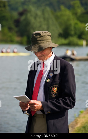 Ein traditionell gekleideter Mann in Blazer und Krawatte tragen ein Leander Club-Abzeichen untersucht die Henley Royal Regatta-Programm. Stockfoto