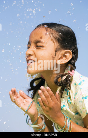 Indisches Mädchen Spritzwasser auf, sich gegen den blauen Himmel. Indien Stockfoto