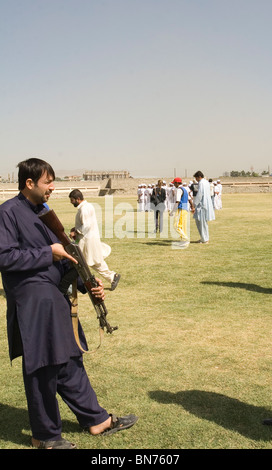 Kinder sind Cricket in Kabul Afghanistan unter bewaffnetem Schutz spielen lernen Stockfoto