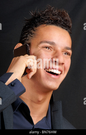 Lächelnde junge Geschäftsmann auf einem Mobiltelefon. Stockfoto