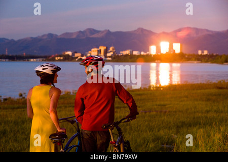 Radfahrer-Reste und und genießt den Sonnenuntergang entlang der Tony Knowles Coastal Trail mit der Verankerung im Hintergrund, Alaska Stockfoto