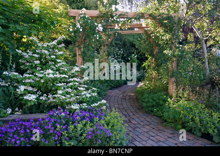 Ziegelstein-Weg durch einen englischen Country-Garten Stockfoto