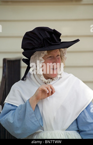 Ein Dolmetscher trägt einer Frau aus dem 18. Jahrhundert auf dem Hut und zeitgenössischer Kleidung in Colonial Williamsburg, Amerikas bekannt lebendige Geschichte Attraktion in Virginia. Stockfoto