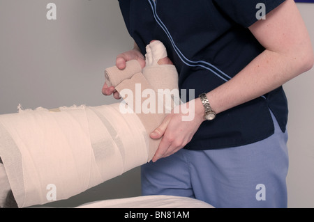 Physiotherapeut Verpackung Bandage um das Bein einer Patientin Stockfoto