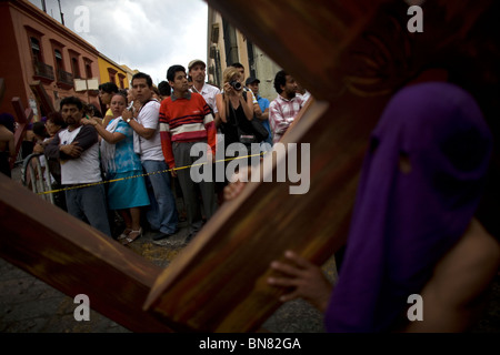 Eine vermummte Büßer trägt ein Kreuz während der Karwoche feiern in Oaxaca, Mexiko, 12. April 2009. Stockfoto