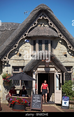 Frau verlässt im Juni das Crab Hotel mit Strohdschaufeln durch die Eingangstür der Familie in Shanklin, Isle of Wight, Hampshire, Großbritannien Stockfoto