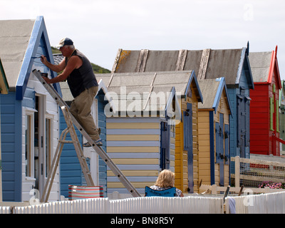 Alte Mann Malerei Strandhütte bereit für den Sommer, Westward Ho!, Devon, UK Stockfoto