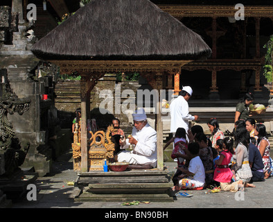 Balinesische Priester, Durchführung einer Zeremonie im Tirta Empul Tempel, ein zweite Priester Weihwasser nutzt, um die Gemeinde segnen. Stockfoto