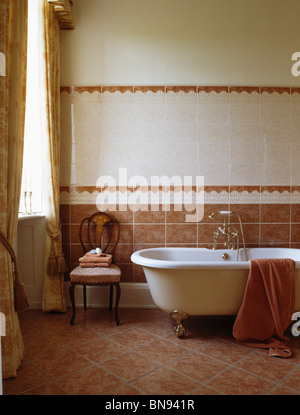 Roll-Top Bad in Terracotta und weiß gefliestes Badezimmer mit