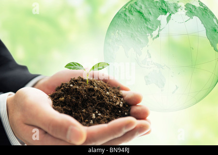Der Mann hält Sämling auf Händen Bild der Kugel auf Hintergrund Computer Graphic Stockfoto