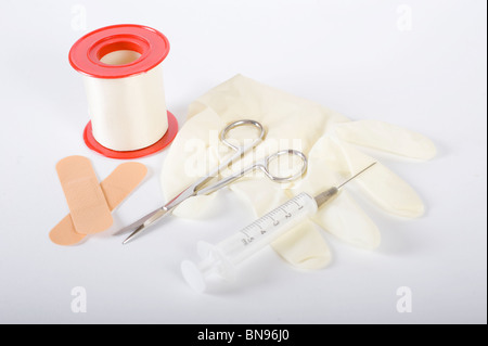 Latex-Handschuhe mit Schere, Pflaster, Klebeband und eine Spritze, isoliert auf weiss Stockfoto
