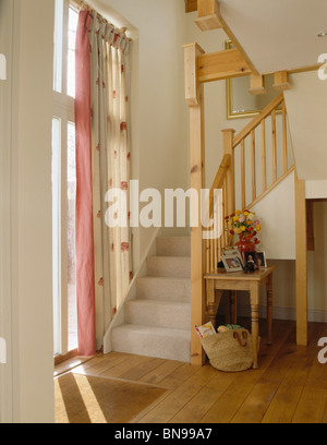 Cremefarbene Teppich auf offene Holztreppe im Weißen Saal mit Creme + rosa gemusterte Vorhänge am Fenster Stockfoto