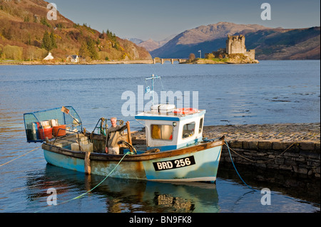 Fischer in Fischerboot & Eilean Donan Castle, Loch Duich, Schottisches Hochland, Schottland Stockfoto