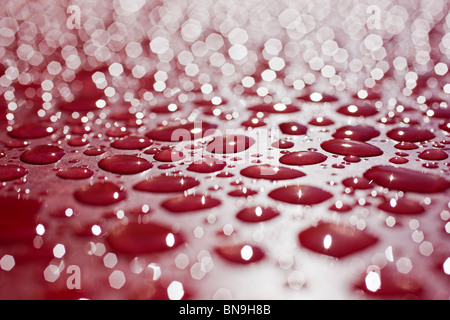 Nahaufnahme Makroaufnahme von Regentropfen auf einem roten Tisch