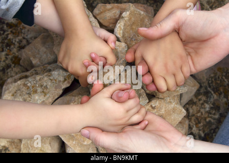 Erwachsenen- und Chilcren Hand in Hand um Stein Kreis Wunsch Wunsch Stockfoto