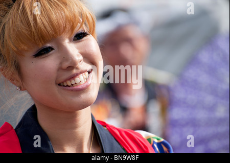 Eine Nahaufnahme der eine junge Japanerin mit gebleichten Haaren und blaue Kontaktlinsen Vorformen eines traditionellen Sonnenschirm-Tanzes. Stockfoto