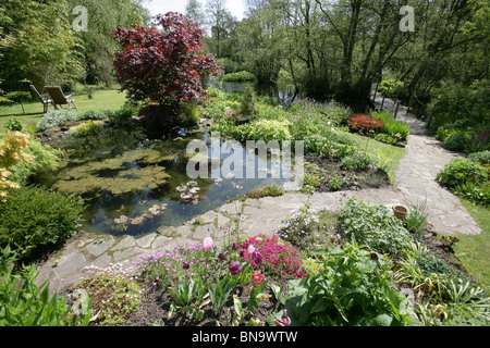 Stonyford Bauerngärten, England. Malerische Frühjahr Blick auf Teich und Blume Grenzen Stonyford Bauerngärten. Stockfoto