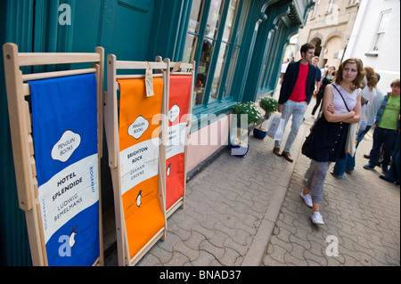 Literarische Liegestühle Marke Penguin Books zum Verkauf vor Geschäft mit Touristen zu Fuß vorbei und stöbern in Hay on Wye Wales UK Stockfoto