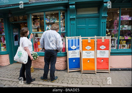 Literarische Liegestühle Marke Penguin Books zum Verkauf vor Geschäft mit Touristen zu Fuß vorbei und stöbern in Hay on Wye Wales UK Stockfoto