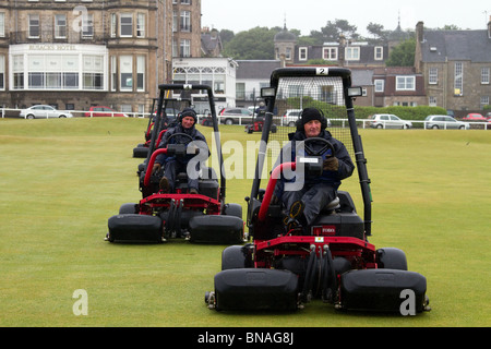 Reiten Greens-mäher Maschinen Grass Cutter und Grünen keepers Mähen der alte Kurs; Team Wartung an die 139. British Open Golf 2010, Juli 15-18, St Andrews, Schottland, Großbritannien. Die Funktion des Mähens, den Golfkurs für Spiel vorzubereiten, obwohl mähen Muster, die oft benutzt werden, sind die Funktionen einer Golfplatz zu markieren. Das Mähen Muster können haben einen großen Einfluss auf das Aussehen der Golfplatz und die Gesundheit der Rasen, während die ihre Arbeits- und Kraftstoffverbrauch. Die häufigsten Fahrrinne mähen Methoden sind Striping, Kontur mähen, der klassische Schnitt, und Schieben und Ziehen. Stockfoto